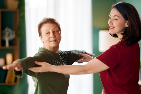 Senior woman doing exercise. A nurse helping with physical therapy at homeの写真素材