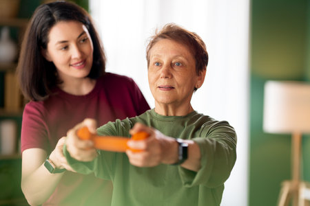 Senior woman doing dumbbell exercise. A nurse helping with physical therapy at homeの写真素材