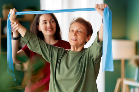 Senior woman doing exercise. A nurse helping with physical therapy at homeの写真素材