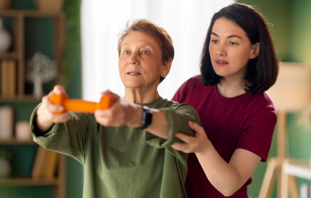 Senior woman doing dumbbell exercise. A nurse helping with physical therapy at homeの写真素材