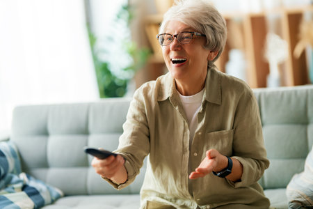 Senior woman watching TV, movies. Retiree spending time at home.