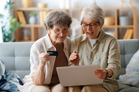 Women are doing online purchases. Senior people are doing shopping using laptop and credit card at home.の写真素材
