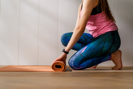 Young woman is rolling yoga mat at home.の写真素材
