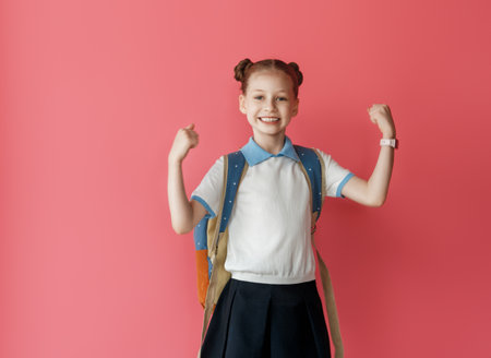 Cute happy teenager standing on bright pink background. Child with backpack, girl is ready to back to school.の写真素材