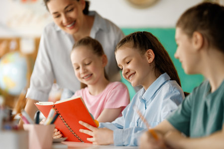 Happy kids and teacher at school. Woman and children are working in the class.の写真素材