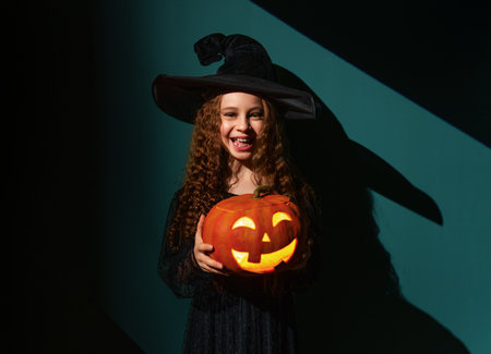 girl in witch costume with Halloween pumpkinの写真素材