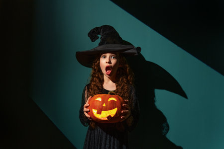 girl in witch costume with Halloween pumpkinの写真素材
