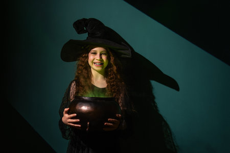 girl in witch costume with pot on Halloween