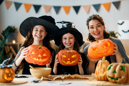 Happy family preparing for Halloween. Mother and children carving pumpkins at home.の写真素材