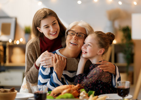 Thanksgiving Day, Autumn feast. Happy family sitting at the table and celebrating holiday. Traditional dinner. Grandmother and granddaughters.の写真素材