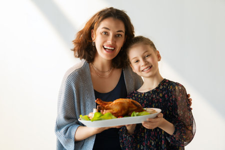Woman and child holding a roast turkey together, preparing for holiday meal.の写真素材