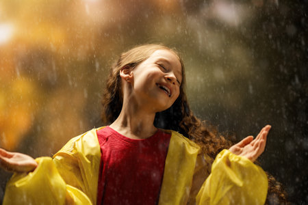 Happy little girl in the rain on an autumn walkの写真素材