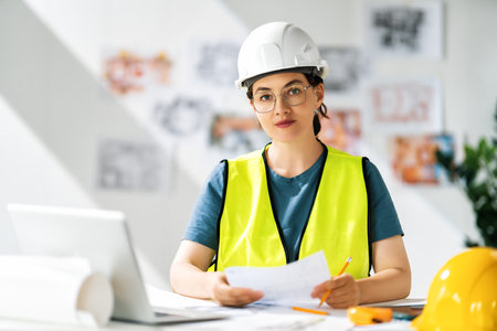 Woman architect is working on plans at construction site.の写真素材