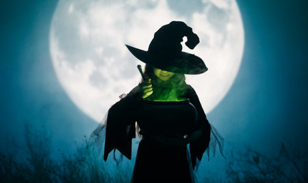 Girl dressed in witch costumes for Halloween. Kid standing on full moon background.の写真素材