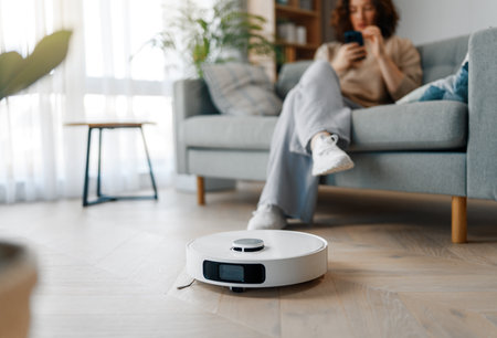 White robotic vacuum cleaner on wooden floor. Smart cleaning technologyの写真素材