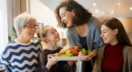 Thanksgiving Day, Autumn feast. Happy family sitting at the table and celebrating holiday. Traditional dinner. Grandmother and granddaughters.の写真素材