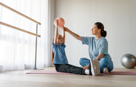 The child is undergoing physical therapy. The girl is doing exercises under the doctor's supervision.の写真素材