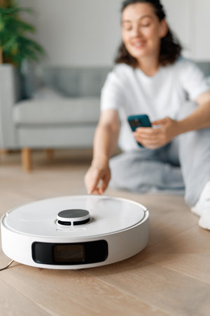 White robotic vacuum cleaner on wooden floor. Smart cleaning technologyの写真素材
