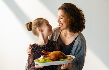 Woman and child holding a roast turkey together, preparing for holiday meal.の写真素材