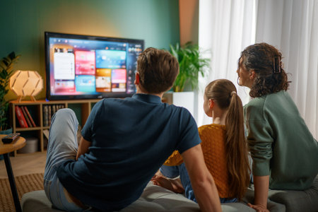 Happy family spending time together. Mother, father and child watching  TV, movies in the evening at...