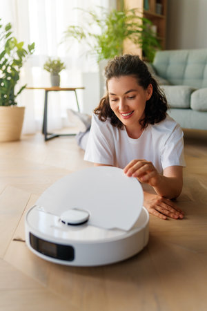White robotic vacuum cleaner on wooden floor. Smart cleaning technologyの写真素材