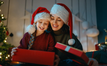 Merry Christmas, Happy Holidays. Mom and daughter with gifts near the tree indoors.の写真素材