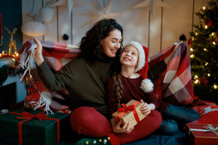 Merry Christmas, Happy Holidays. Mom and daughter with gifts near the tree indoors.の写真素材
