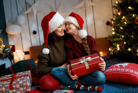 Merry Christmas, Happy Holidays. Mom and daughter with gifts near the tree indoors.の写真素材