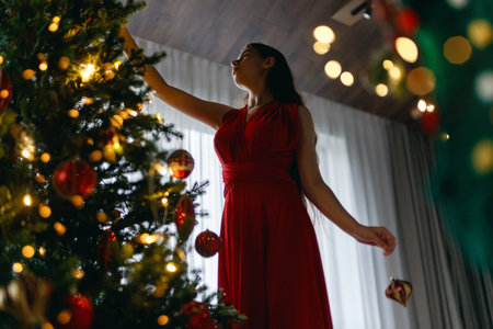 Happy young beautiful woman near Christmas tree indoor.の写真素材