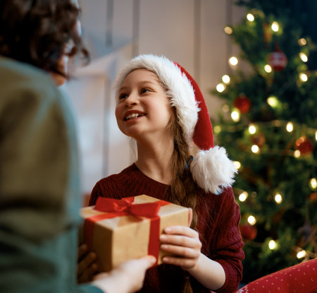 Merry Christmas, Happy Holidays. Mom and daughter with gifts near the tree indoors.の写真素材