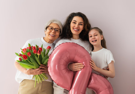 Happy women's day! Child daughter is congratulating mom and grandmother giving them flowers tulips....
