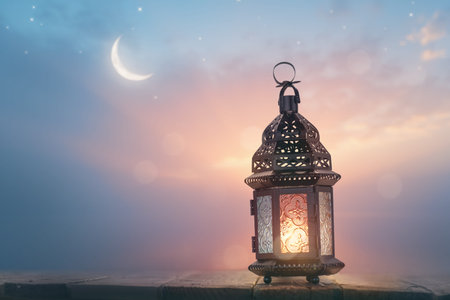 Ornamental Arabic lantern with burning candle glowing at night. Festive greeting card, invitation...