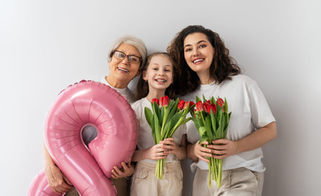 Happy women's day! Child daughter  is congratulating mom and grandmother giving them flowers tulips....