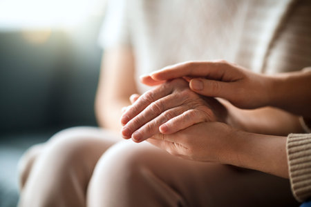 Adult daughter comforting old mom, stroking holds her hand, close up view.