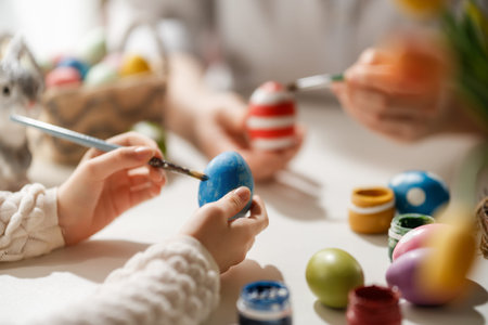Joyful and heartwarming scene of hands painting colorful Easter eggs, capturing the warmth and creativity of a family spending quality time together. Perfect for illustrating holiday traditions, DIY crafts, childhood memories, and festive celebrations in a bright, inviting home environment. The soft lighting and vibrant colors convey happiness, bonding, and the spirit of Easter festivities.の写真素材