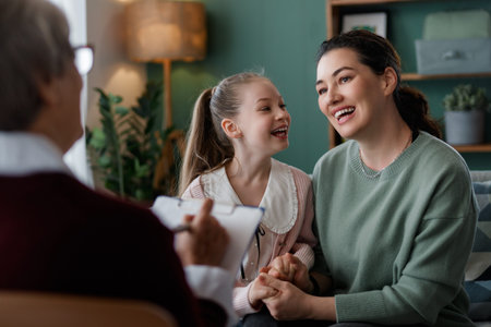Heartwarming image of a mother and daughter smiling during a positive family therapy session. The setting is warm and inviting, showcasing emotional connection and professional counseling.の写真素材