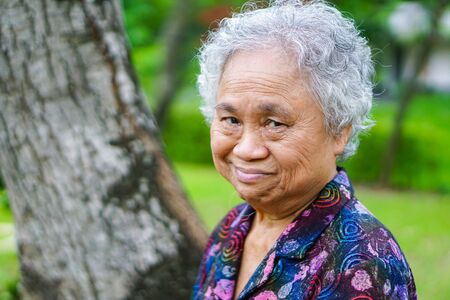 Asian senior or elderly old lady woman eighty years with smile bright face while standing in park :...
