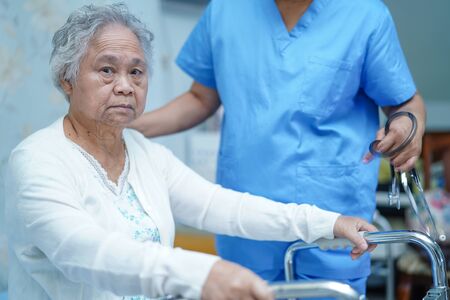 Asian nurse physiotherapist doctor care, help and support senior or elderly old lady woman patient walk with walker at hospital ward : healthy strong medical concept.の写真素材