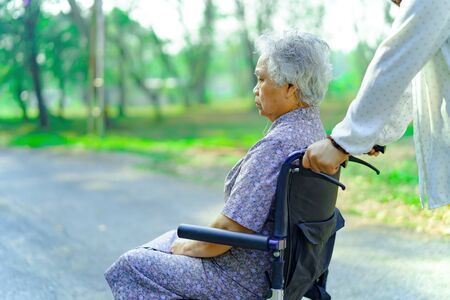 Asian senior or elderly old lady woman patient with care, help and support on wheelchair in park in holiday: healthy strong medical concept.の写真素材