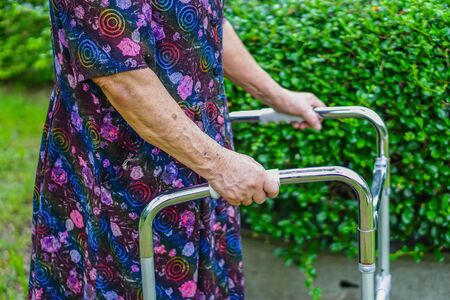 Asian senior or elderly old lady woman patient walk with walker in park : healthy strong medical conceptの写真素材