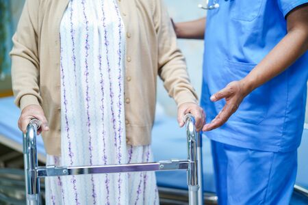 Asian nurse physiotherapist doctor care, help and support senior or elderly old lady woman patient walk with walker at hospital ward : healthy strong medical concept.の写真素材