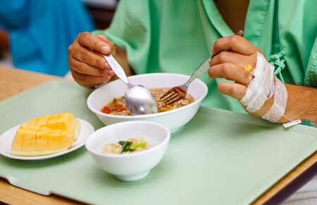Asian  lady woman patient eating breakfast healthy food with hope and happy while sitting and hungry on bed in hospital.の写真素材