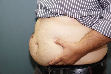 Overweight Asian woman show fat belly at office.の写真素材