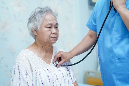 Doctor using stethoscope to checking the patient lie down on a bed in the hospital ward : healthy strong medical conceptの写真素材