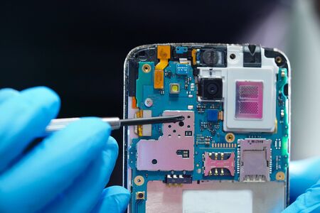 Asian Technician repairing micro circuit main board of smartphone electronic technology : computer,...