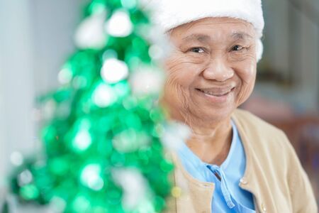 Asian senior or elderly old lady woman patient with Santa Claus helper hat very happy in christmas and new year celebration festival holiday party in hospital. の写真素材