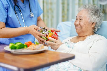 Asian senior or elderly old lady woman patient eating breakfast healthy food with hope and happy while sitting and hungry on bed in hospital.の写真素材