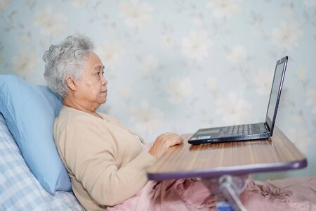 Asian senior or elderly old lady woman patient using notebook computer and smile with doctor while...
