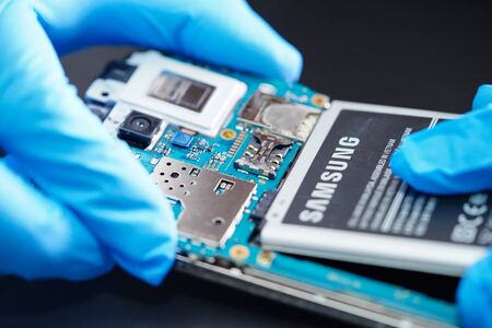 BANGKOK,THAILAND.DECEMBER 5,2019: technician repairing and insert battery for Smartphone SAMSUNG.のeditorial素材