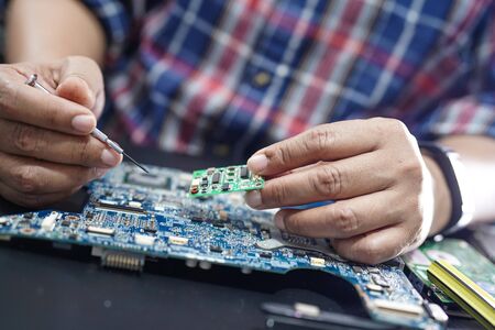 Technician repairing inside of hard disk by soldering iron. Integrated Circuit. the concept of data,...